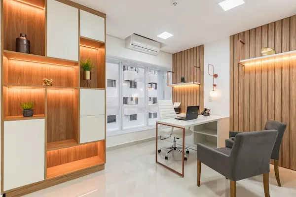 Consultório com estante iluminada e mesa de atendimento